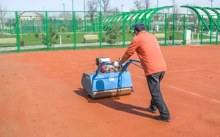 man repairing clay sport court