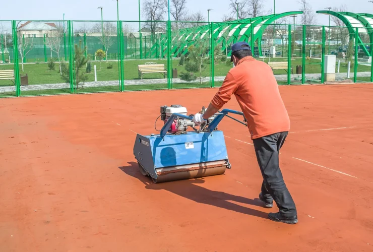 man repairing clay sport court