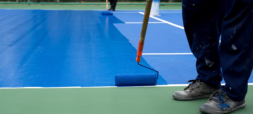 Man painter use paint roller painting tennis court in blue color