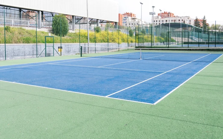 asphalt tennis court with a blue and green surface, located in a large sports complex