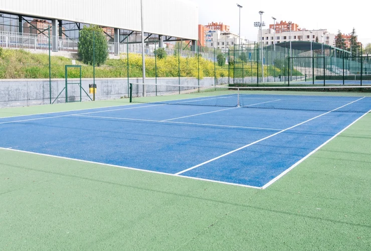 asphalt tennis court with a blue and green surface, located in a large sports complex