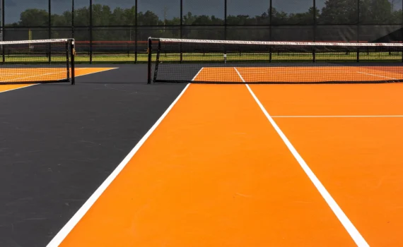 Tennis court net and post on orange and black tennis court