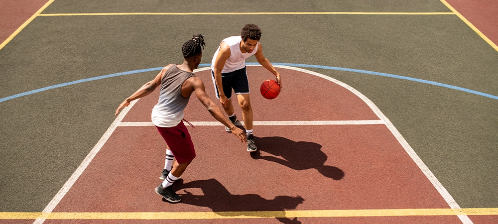 Two Young Adults Playing Basketball on Outdoor Court