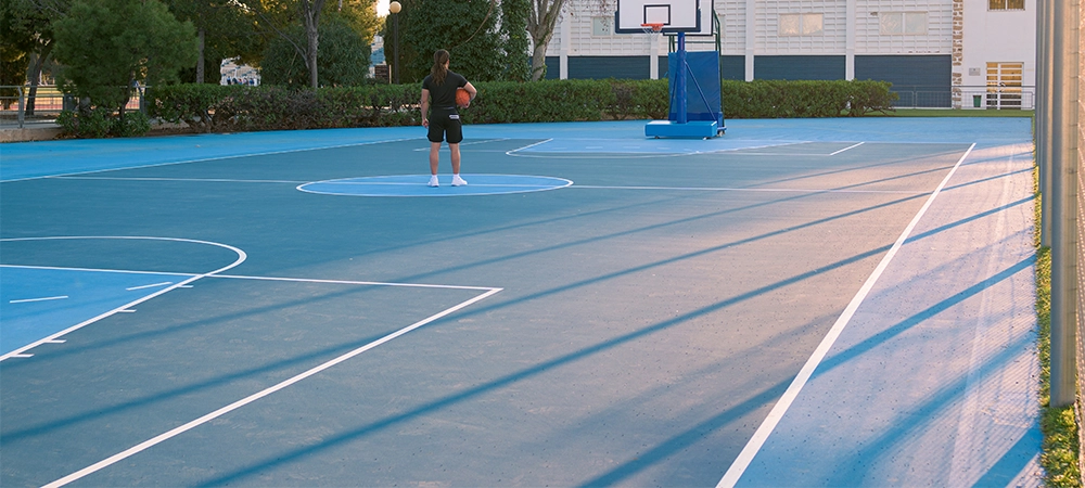Basketball court with one person in the middle looking to the basket