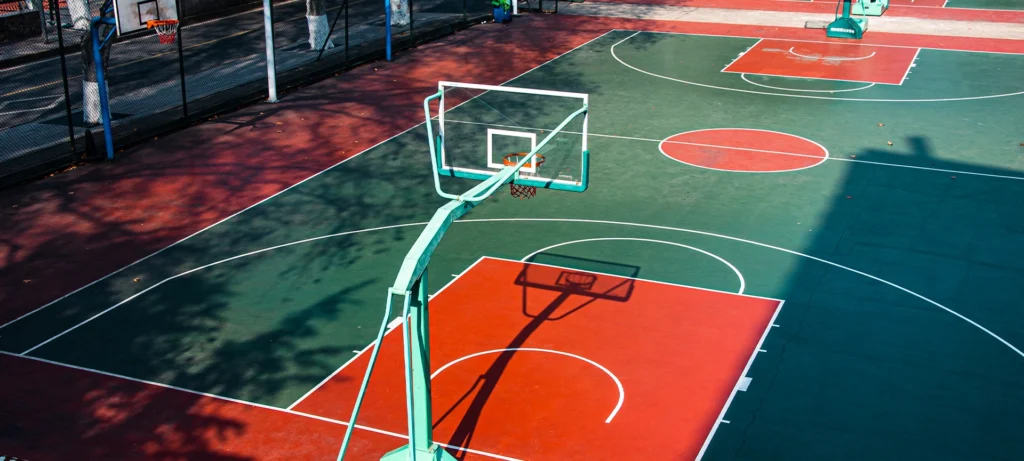 Open college basketball court, with bright colors, illuminated by the warm noon sunshine.