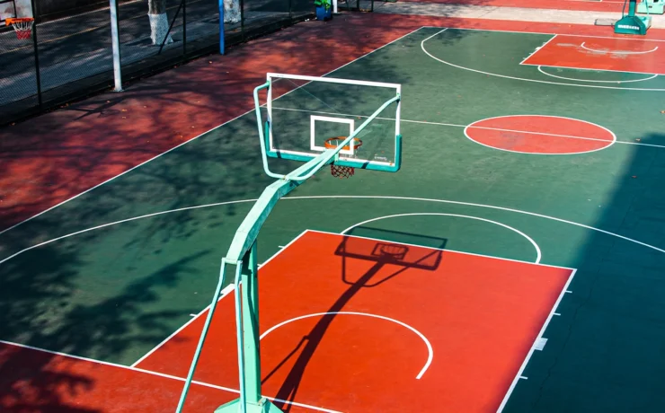 Open college basketball court, with bright colors, illuminated by the warm noon sunshine.
