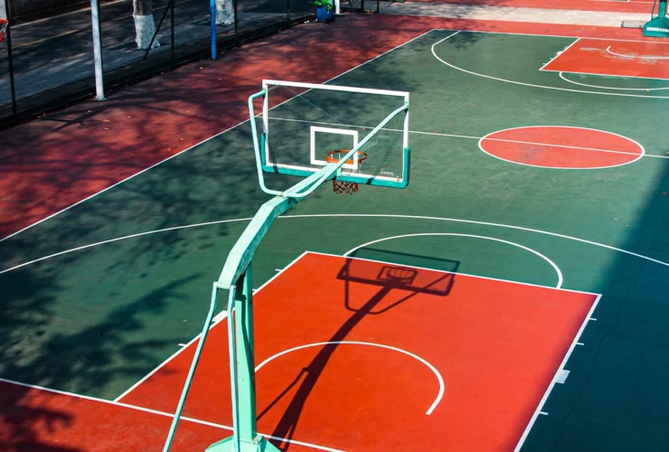Open college basketball court, with bright colors, illuminated by the warm noon sunshine.