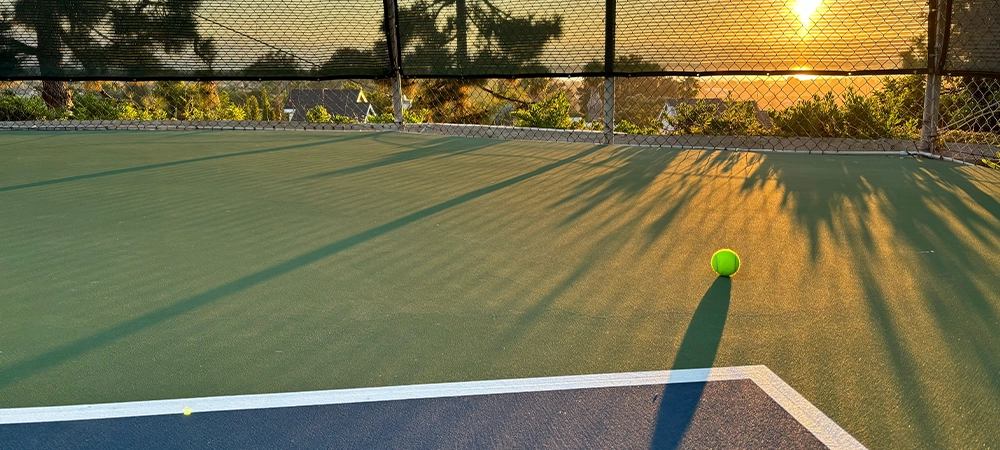 Sun setting over the tennis court. Close up tennis ball on the court