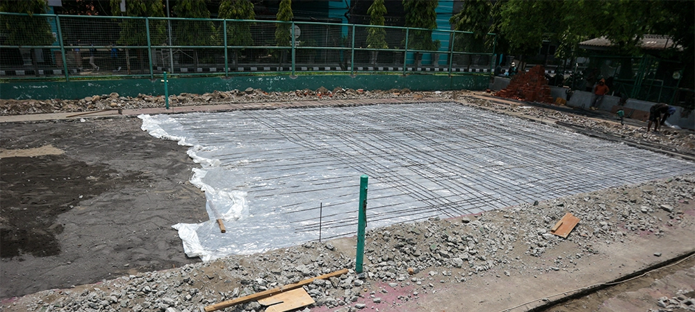 work on installing floor slab reinforcement for tennis courts. and there is plastic underneath to hold the water so it doesn't go straight to the ground