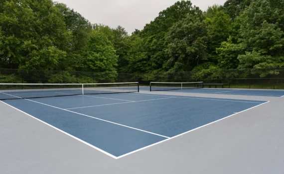 Blue tennis court with white lines and gray out of bounds