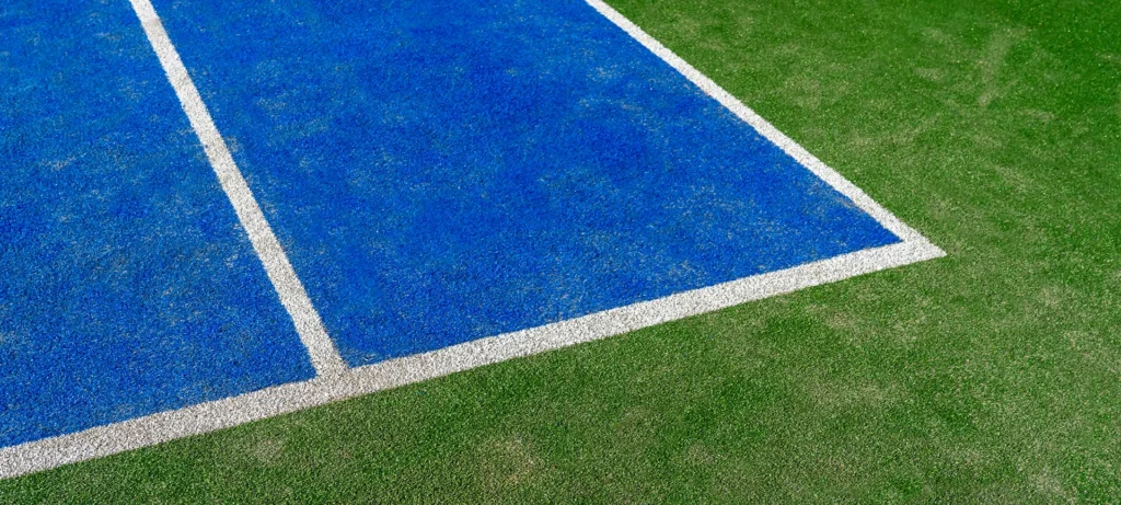 Detail of a new synthetic tennis court. White lines on a blue artificial grass tennis court. Racket sports concept