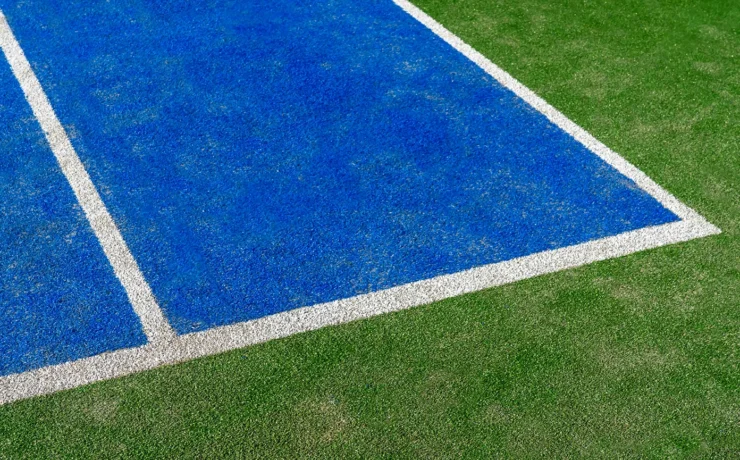 Detail of a new synthetic tennis court. White lines on a blue artificial grass tennis court. Racket sports concept