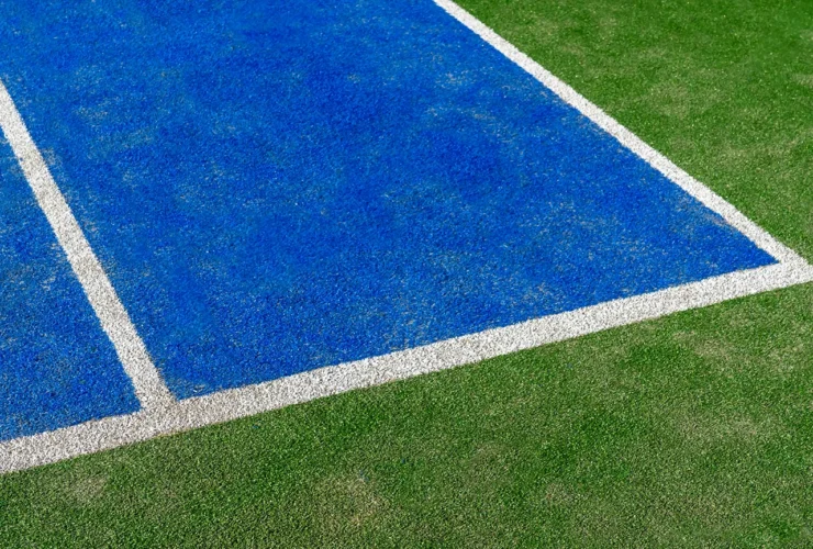 Detail of a new synthetic tennis court. White lines on a blue artificial grass tennis court. Racket sports concept