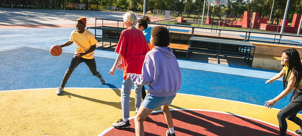 Young Adults Playing Basketball Outside on Colorful Court