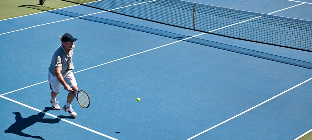 Sport, man and tennis on court with fitness, competition and performance outdoor with match and energy. Power, athlete and ball on turf for training, health and racket with skill, game or hobby