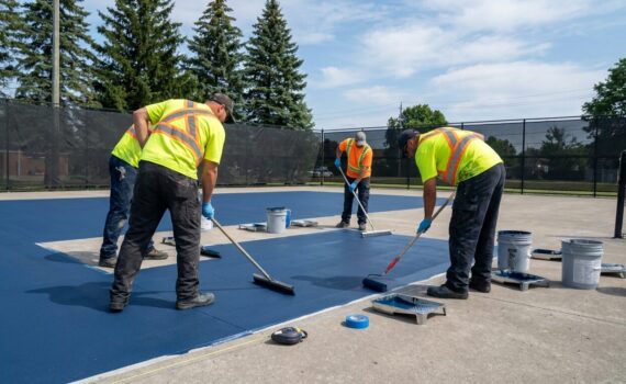 Crew resurfacing an outdoor tennis court in Ontario before a pickleball conversion