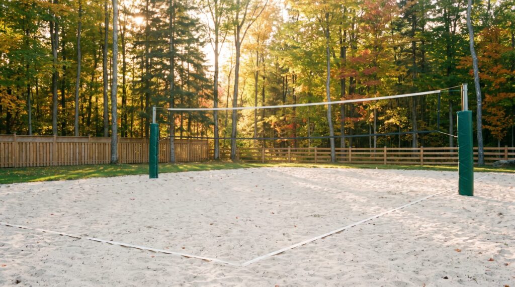 Backyard sand volleyball court with a taut net on padded posts, level sand and maple trees behind a cedar fence in Ontario