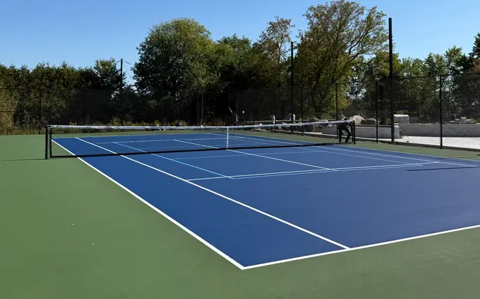 Blue and green acrylic tennis court with light blue pickleball lines and black chain-link fence