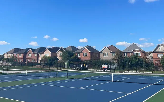 Pair of blue and green tennis courts with nets in a residential neighbourhood